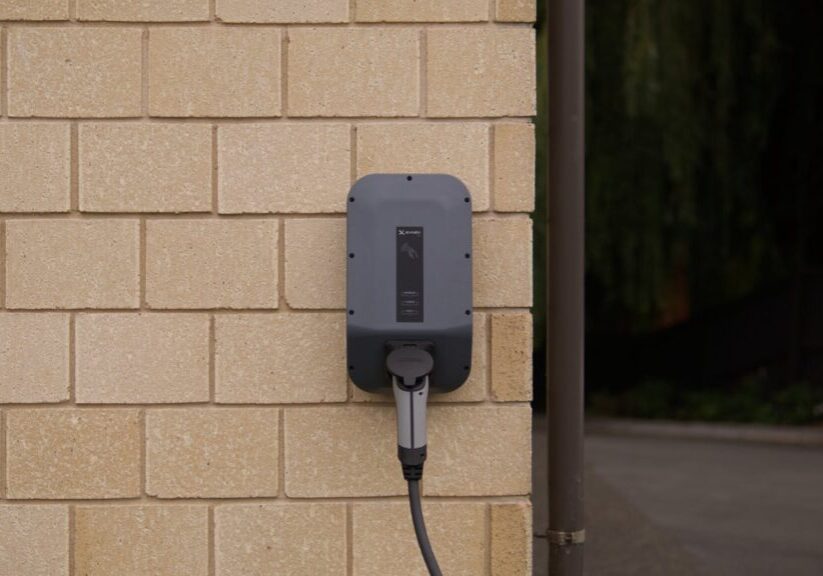 Level 2 wall-mounted EV charger at a home, illustrating Tesla Wall Connector vs J1772 comparison